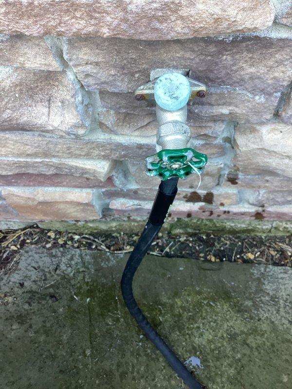Responded to outdoor faucet dripping issue when hose attachment was connected. Inspected hose bib mounted on brick exterior and identified leak occurring at connection point with green Y-splitter adapter. Evaluated spigot assembly, rubber washers, and threading on both the hose bib and connector to determine source of water loss. Completed necessary repairs to eliminate dripping and restore proper seal at hose connection point.
