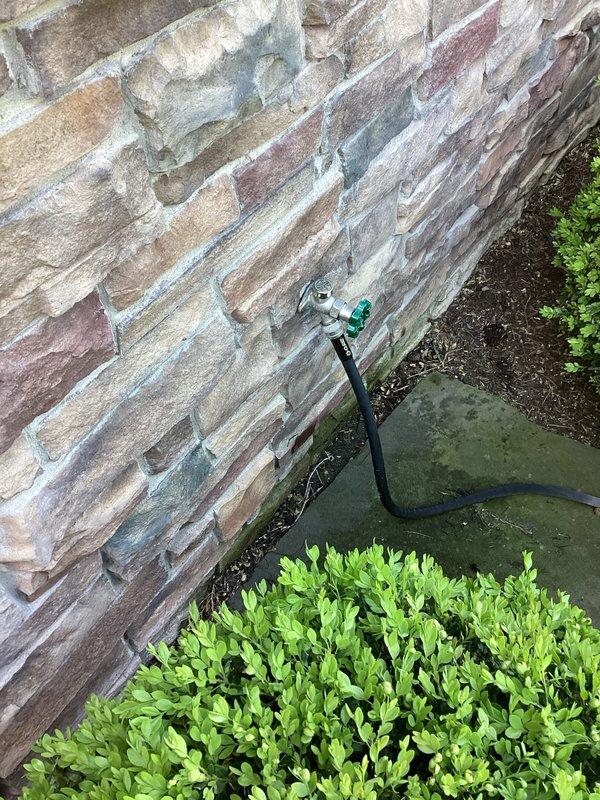 Responded to outdoor faucet dripping issue when hose attachment was connected. Inspected hose bib mounted on brick exterior and identified leak occurring at connection point with green Y-splitter adapter. Evaluated spigot assembly, rubber washers, and threading on both the hose bib and connector to determine source of water loss. Completed necessary repairs to eliminate dripping and restore proper seal at hose connection point.
