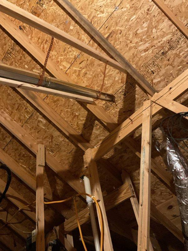 Conducted plumbing estimate for gas water heater venting installation to replace existing electric unit in residential mechanical room. Assessed attic space and structural framing to determine proper flue pipe routing through ceiling joists and roof penetration. Evaluated existing dual water heater configuration including gas-fired unit and insulated storage tank for geothermal system, along with water filtration equipment, to provide comprehensive venting solution and ensure code-compliant installation for converted gas appliance.