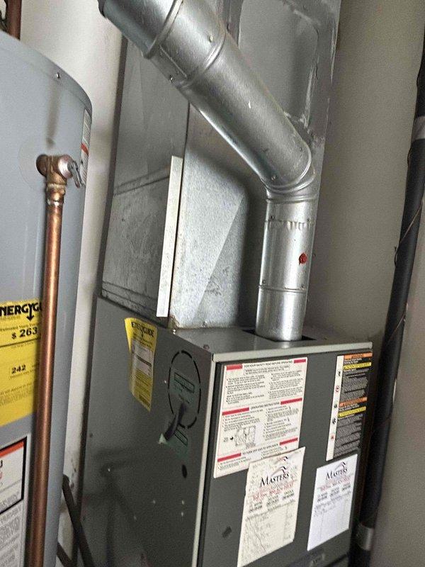 Conducted on-site assessment of existing 25-year-old Trane HVAC system for complete gas furnace and air conditioning replacement estimate. Evaluated current furnace unit located in utility room, documenting existing equipment configuration, ductwork connections, and installation parameters. Photographed existing mechanical systems including furnace positioning, metal ductwork routing from unit to ceiling, and surrounding utility room layout to determine replacement specifications. Assessed electrical connections, gas line access, condensate drainage requirements, and available clearances for new equipment installation. Evaluated existing ductwork condition and connections to determine compatibility with replacement system. Documented water heater proximity and PVC plumbing lines along walls to ensure proper clearances and code compliance for new furnace installation. Prepared comprehensive replacement estimate for complete gas furnace and air conditioning system upgrade.