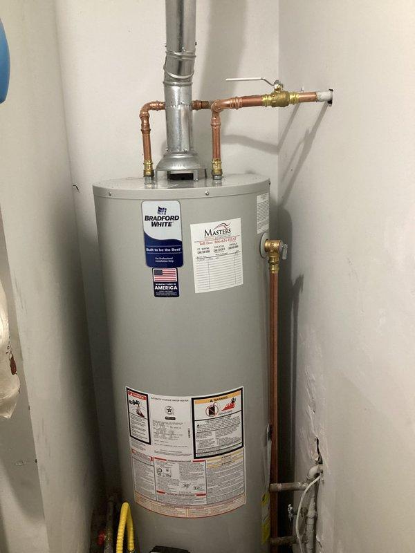 Completed installation of a Bradford White tanked gas water heater in residential utility room. Removed existing water heater unit and installed new tank with proper copper piping connections, brass shut-off valves, and compression fittings at inlet and outlet ports. Configured galvanized metal vent pipe system with insulated ductwork penetrating through ceiling for proper exhaust ventilation. Installed pressure relief valve, drain valve, and leveling supports at base of unit. All plumbing connections soldered and secured to manufacturer specifications. Obtained and completed installation under proper permitting. System tested and verified operational upon completion.