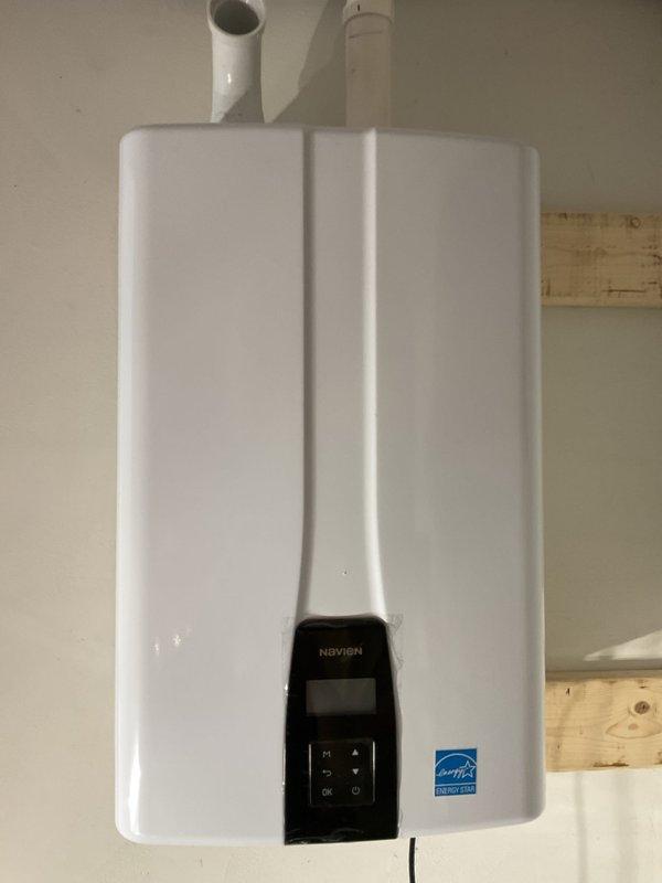 Completed full installation of Navien NPE-240A2 tankless natural gas water heater. Ran new gas line from existing supply, routed flue pipe to exterior for proper venting, and installed water supply and drain lines to unit specifications. Unit mounted securely to wall with all connections properly configured and tested for safe operation.
