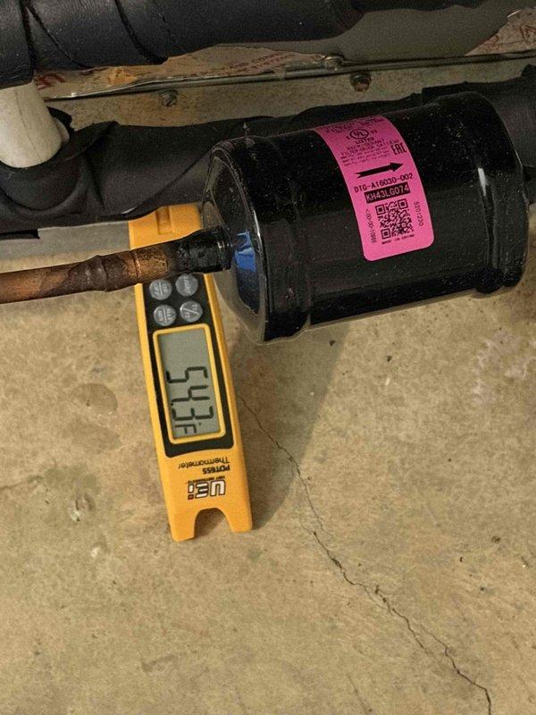 Performed routine maintenance inspection on residential cooling system. Checked and documented system temperatures, recording 53.8°F reading at filter drier/accumulator component using digital diagnostic instrument. Inspected electrical components including capacitor, contactor relay, and associated wiring connections within unit cabinet, verifying all connections were secure and components showed normal operating condition.