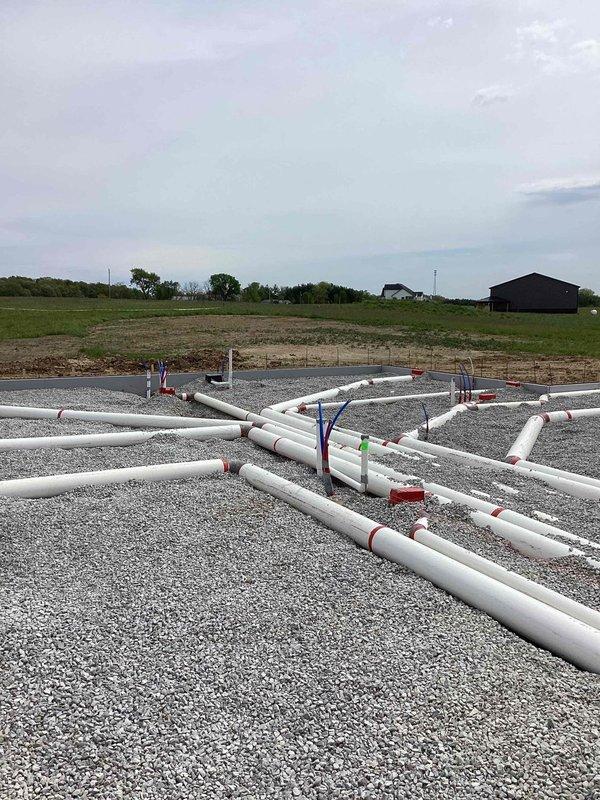 Completed underground ductwork installation for new residential construction. Multiple PVC duct runs were positioned and secured on prepared gravel foundation with proper support brackets and spacing in accordance with building specifications. All ductwork was properly marked, reinforced with rebar placement for concrete pour integration, and secured with fabric strapping to maintain alignment during foundation completion phase.