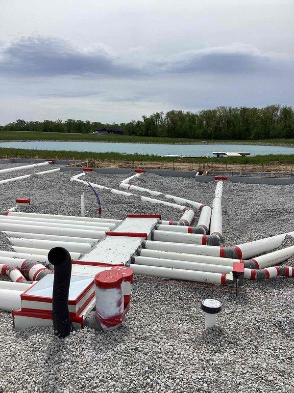 Completed underground ductwork installation for new residential construction. Multiple PVC duct runs were positioned and secured on prepared gravel foundation with proper support brackets and spacing in accordance with building specifications. All ductwork was properly marked, reinforced with rebar placement for concrete pour integration, and secured with fabric strapping to maintain alignment during foundation completion phase.
