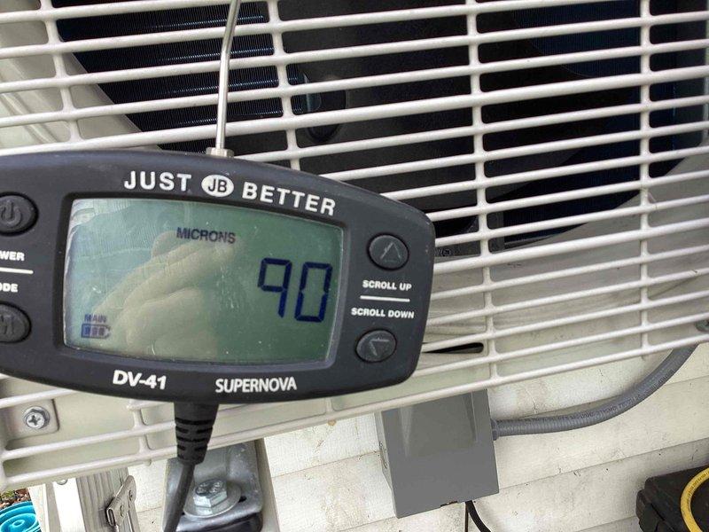 Returned to complete refrigerant charge adjustment on backup heat pump system that requires R32 refrigerant. System was previously serviced but charge could not be properly dialed in due to cold ambient temperatures below 65°F. With warmer weather conditions now present, performed vacuum test showing system holding at 90 microns, confirming system integrity. Proceeded to add R32 refrigerant and dialed in charge to manufacturer specifications for optimal system performance.