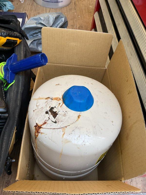 Responded to emergency call for ceiling collapse caused by failed water heater. Upon arrival, found extensive water damage from corroded and leaking pressure tank system. Removed heavily rusted cylindrical pressure tank showing significant corrosion, rust streaking, and structural deterioration. Replaced failed pressure tank with new Werner blue pressure tank (unit #34626) and installed alongside existing water heater. Reconnected copper supply lines with new fittings, installed pressure relief valve, and mounted pressure gauge for system monitoring. Tested all connections for leaks and verified proper system pressure. Advised customer that ceiling repairs would require separate contractor for drywall restoration work.