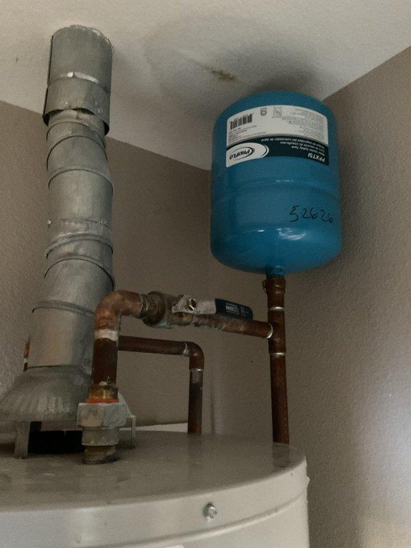 Responded to emergency call for ceiling collapse caused by failed water heater. Upon arrival, found extensive water damage from corroded and leaking pressure tank system. Removed heavily rusted cylindrical pressure tank showing significant corrosion, rust streaking, and structural deterioration. Replaced failed pressure tank with new Werner blue pressure tank (unit #34626) and installed alongside existing water heater. Reconnected copper supply lines with new fittings, installed pressure relief valve, and mounted pressure gauge for system monitoring. Tested all connections for leaks and verified proper system pressure. Advised customer that ceiling repairs would require separate contractor for drywall restoration work.