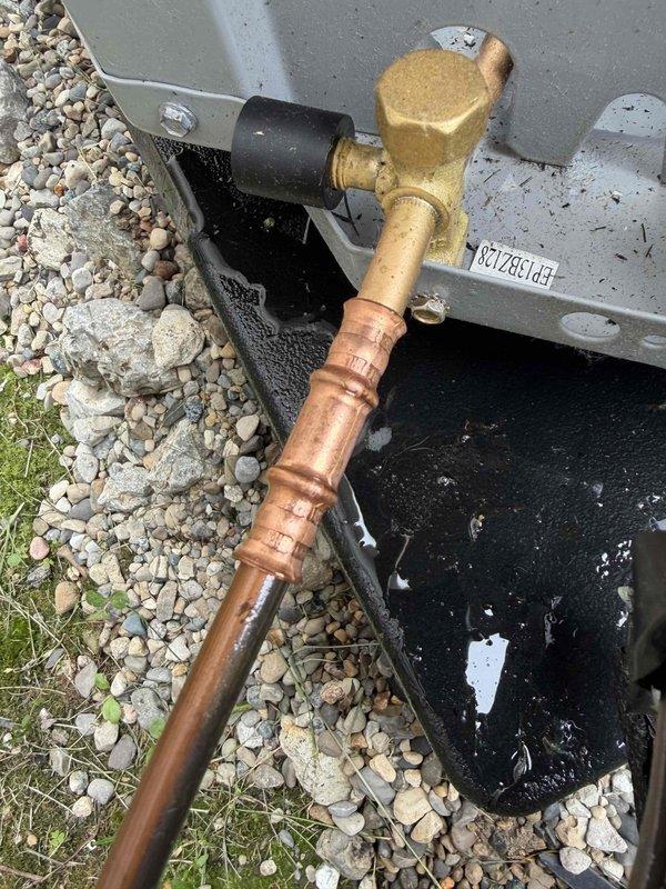 Responded to no-cooling callback for AC unit displaying 10.2 error code indicating low refrigerant. Upon inspection, identified active refrigerant leak at outdoor unit's brass valve assembly and copper line connections, evidenced by clear oil residue and visible corrosion on copper piping. Documented condition of weathered service valves, oxidized copper lines, and compromised connection points for repair authorization.