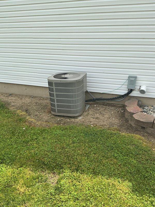 Completed estimate for furnace and air conditioning replacement at rental property. Evaluated existing beige forced-air furnace located in basement utility room with blue insulated ductwork and assessed outdoor AC condenser unit with tan metal housing positioned on concrete pad against building exterior. Documented current system configuration including refrigerant lines, electrical disconnect, and ductwork connections to provide comprehensive replacement recommendations for both heating and cooling equipment.