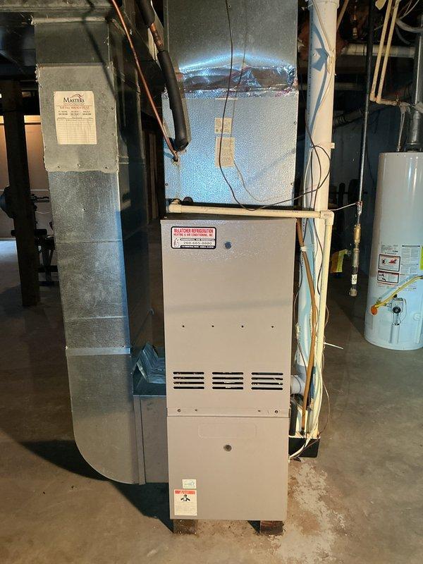 Completed estimate for furnace and air conditioning replacement at rental property. Evaluated existing beige forced-air furnace located in basement utility room with blue insulated ductwork and assessed outdoor AC condenser unit with tan metal housing positioned on concrete pad against building exterior. Documented current system configuration including refrigerant lines, electrical disconnect, and ductwork connections to provide comprehensive replacement recommendations for both heating and cooling equipment.