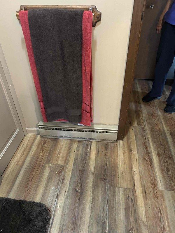 Responded to service call for malfunctioning bathroom heating system. Assessed existing baseboard heater installation running along floor level beneath towel rack area. Provided estimate for replacement of non-functioning under-floor heating unit and evaluated thermostat control system mounted on adjacent wall to ensure compatibility with new equipment.