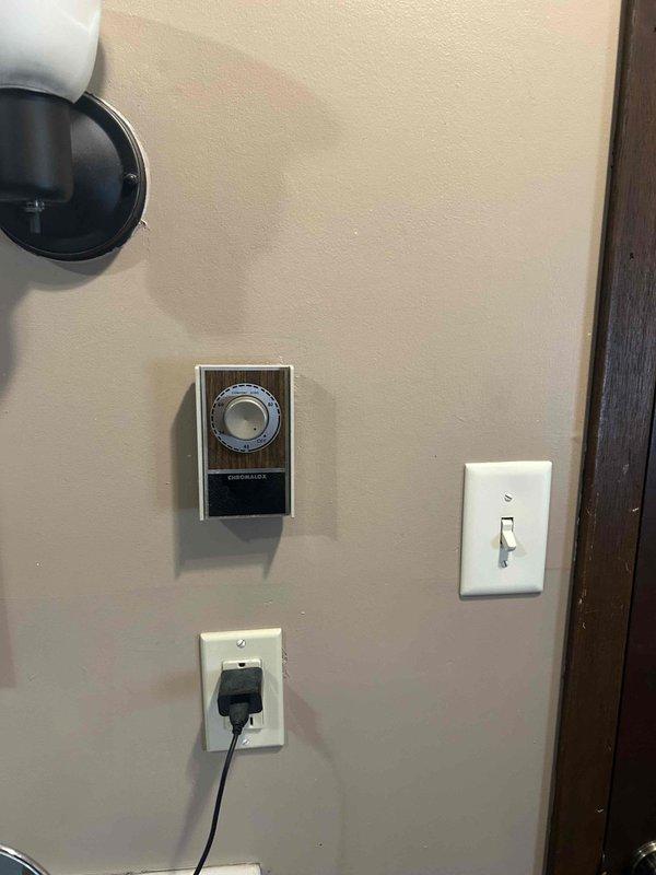 Responded to service call for malfunctioning bathroom heating system. Assessed existing baseboard heater installation running along floor level beneath towel rack area. Provided estimate for replacement of non-functioning under-floor heating unit and evaluated thermostat control system mounted on adjacent wall to ensure compatibility with new equipment.