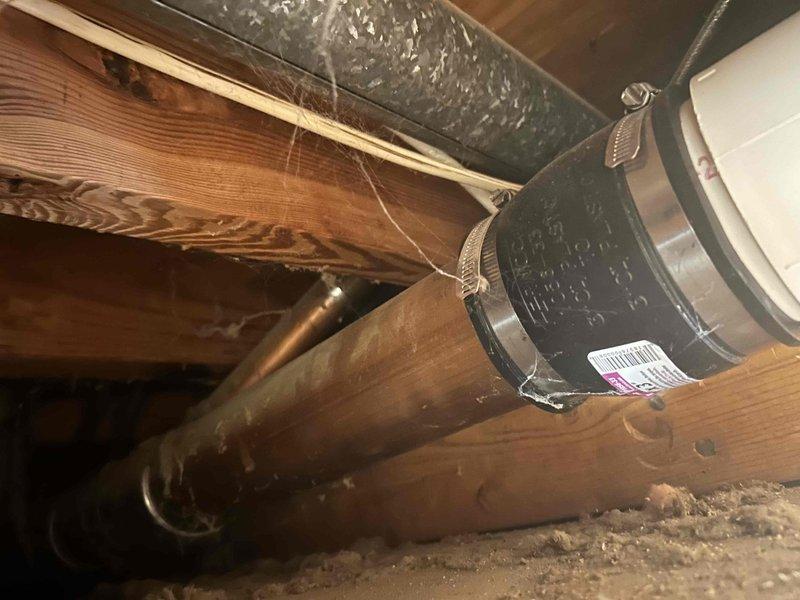 Conducted comprehensive assessment of aging HVAC system and water heating equipment for replacement estimate. Evaluated 20+ year-old air conditioning unit and 10-year-old tanked water heater, both currently operational but nearing end of service life. Inspected attic space and accessed ceiling cavity to assess existing ductwork configuration, support systems, and plumbing infrastructure. Documented metallic ductwork secured to floor joists with metal strapping, PVC plumbing lines, and structural framing conditions. Photographed installation locations and surrounding infrastructure to determine equipment replacement requirements, clearances, and access considerations for future installation work.