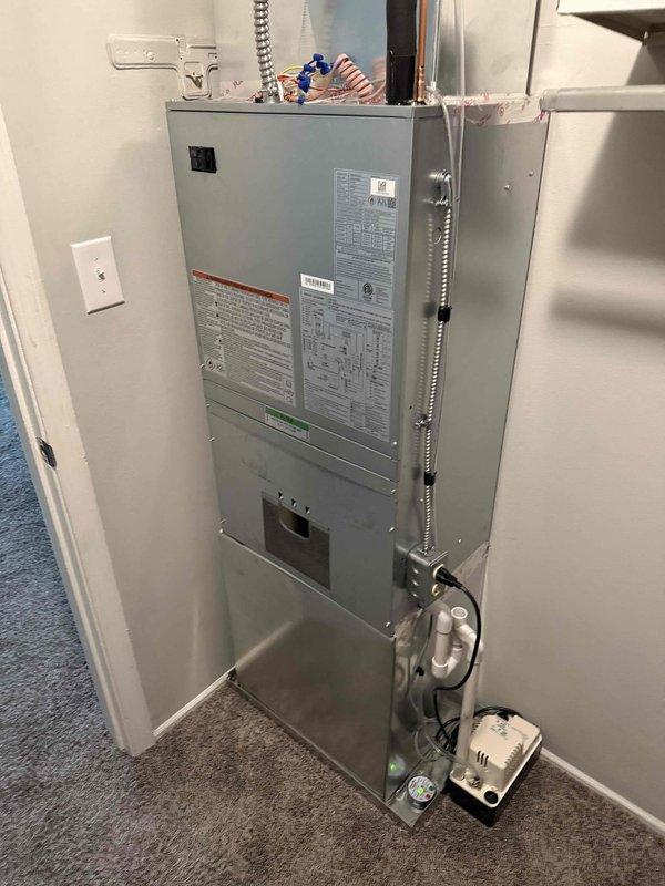 Completed full HVAC system replacement at apartment unit, removing obsolete 1.5 ton R22 ceiling-mounted fan coil and matching outdoor condenser. Installed new Carrier FMA5X2400AL 1.5 ton wall-mounted fan coil with 8kW electric strip heat and Carrier GA4SAN51800N 1.5 ton 14 SEER single-stage air conditioner utilizing R454 refrigerant. Cut open ceiling and wall sections to access existing ductwork, reconnected all duct connections, condensate drain line, and electrical power supply. Extended existing line set with additional 25' section, flushed and pressure-tested refrigerant lines for reuse. Mounted outdoor unit on new PVC pad with electrical disconnect and whip. Installed Honeywell T6 programmable thermostat for system control. Performed complete system startup, evacuated lines, charged unit to manufacturer specifications, and verified proper operation of heating and cooling modes. Removed and hauled away all old equipment from premises.