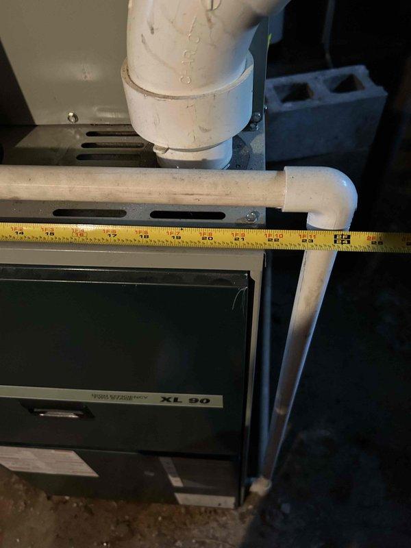 Responded to service call for AC unit freezing up. Upon inspection, documented existing HVAC system configuration including indoor XL 80 furnace unit with associated PVC vent piping and outdoor Trane condensing unit. Measured and photographed current installation setup showing horizontal PVC venting with 90-degree elbows, mounting brackets, and refrigerant line connections between indoor and outdoor components. Assessed complete system for replacement estimate, noting equipment positioning on concrete pad adjacent to building exterior with proper condensate drainage and electrical connections in place.