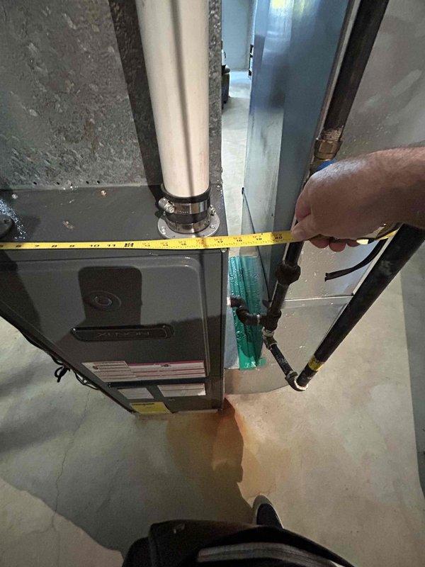 Completed on-site assessment for residential air conditioning system replacement. Evaluated existing HVAC equipment installation in basement mechanical room, including furnace and air handler configuration. Documented current system layout, clearance measurements, and spatial constraints for proposed equipment replacement. Assessed ductwork connections, refrigerant line routing, and condensate drainage pathways. Photographed existing installation showing equipment positioning on concrete floor, PVC drainage piping, metal ductwork plenum, and flexible refrigerant lines. Verified available space for new equipment installation and identified necessary modifications to accommodate replacement system. Provided comprehensive estimate for complete air conditioning system replacement to restore cooling functionality.