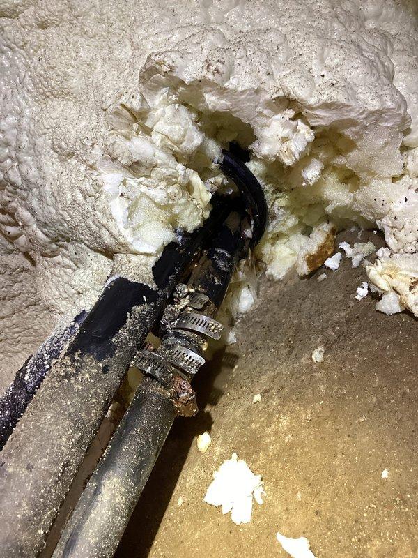 Responded to water leak on well water line in basement. Located leak at pipe penetration through spray foam insulation near pressure tank and well system piping. Assessed PVC plumbing configuration and identified dripping connection point in copper supply line. Tightened fitting connections and verified leak repair, confirming well pump cycle returned to normal operation without continuous running.