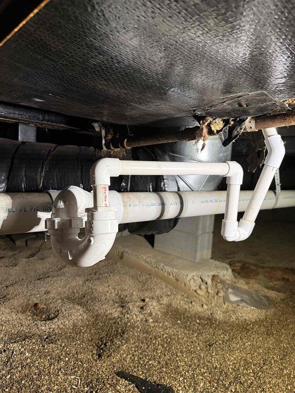 Successfully tied AC condensate drain line into the existing 3" main drain system in the crawl space. Installed white PVC piping with proper P-trap configuration to ensure adequate drainage and prevent airflow issues. All connections were secured and tested to verify proper operation and compliance with plumbing codes.