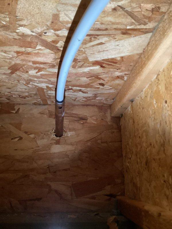 Responded to reported water leak in basement suspected to originate from outdoor water spigot. Upon investigation, accessed ceiling cavity to trace water source and inspect plumbing infrastructure. Located PVC piping running through ceiling joists with compromised penetration point showing signs of water intrusion. Identified corroded metal pipe collar at ceiling penetration as primary leak source, with visible rust and oxidation indicating prolonged moisture exposure. Created access opening in ceiling drywall to facilitate inspection and repair of affected area. Documented conditions with photographs showing extent of water damage and deteriorated pipe flange. Assessed routing of water supply line serving exterior hose bib and confirmed connection point as leak origin.