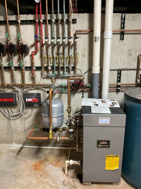 Responded to no hot water complaint on combination boiler system providing both space heating and domestic hot water. Upon arrival, found Panasonic digital control panel displaying standby mode with energy-saving features activated. Previous technician had addressed drain line obstruction during recent service call. Inspected hydronic heating system including manifold assembly with multiple zone valves, expansion tank, and copper distribution piping. Verified all shut-off valves, brass fittings, and PVC condensate drain lines for proper operation. Cleared blockage from drain pipe as recommended by heating technician from prior visit. Cycled system through operating modes and confirmed restoration of domestic hot water production. System returned to normal operation with proper temperature output.