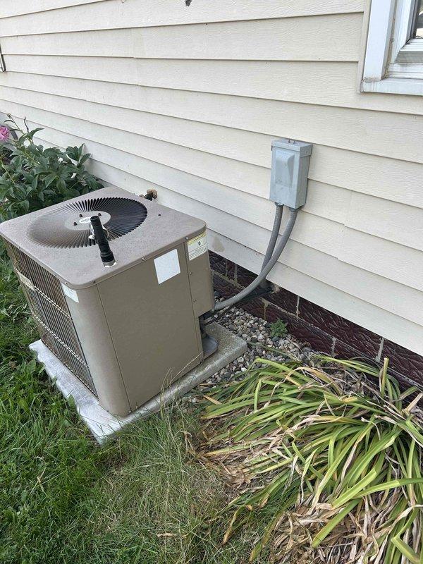 Tech lead Dennis conducted a comprehensive HVAC system evaluation for equipment replacement. Assessment included inspection of existing outdoor air conditioning condenser unit installed on concrete pad with proper electrical disconnect, and aging A.O. Smith ProMax water heater dated from 2009 located in utility area beneath staircase. Documentation through photography captured current equipment conditions, installation configurations, and surrounding service access areas to provide accurate replacement specifications and system upgrade recommendations.
