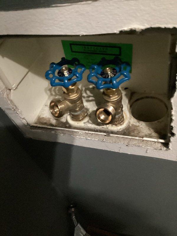 Responded to service call for washing machine installation issue where water supply could not be shut off. Successfully replaced or repaired malfunctioning shut-off valves in recessed Waterite wall box, installing new brass ball valves with blue handles to control hot and cold water lines. Verified proper operation of both valves, ensuring complete water shut-off capability for safe appliance installation and future maintenance access.