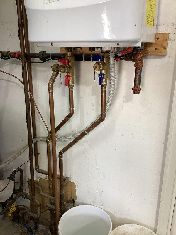 Responded to service call for tankless water heater displaying red error light and complete loss of hot water production. Unit had been previously flushed with vinegar solution by homeowner, which temporarily restored function for several days before failure recurred. Initial troubleshooting revealed unit was non-responsive to standard reset procedures via power cycling. Conducted comprehensive diagnostic inspection of wall-mounted tankless unit, examining all electrical connections, venting system including dual PVC exhaust pipes, and copper supply/return plumbing connections. Assessed control board error codes and evaluated heat exchanger condition for potential scale buildup or component failure. Documented existing installation configuration including proximity to HVAC humidifier system and current plumbing arrangement with multiple shut-off valves. Photographed unit condition, manufacturer labels, and associated plumbing infrastructure for service records. Based on diagnostic find