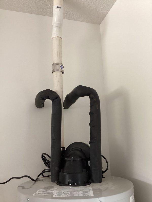 Responded to service call for gas water heater producing unusual noise during operation. Upon arrival, inspected Bradford White 50-gallon natural gas water heater model RG1PV50S6N19 with power vent system. Evaluated the black power vent assembly and associated components mounted on top of unit. Examined PVC venting system running vertically from unit to ceiling. Documented equipment condition and installation specifications including 40,000 BTU/hr input rating and proper clearances for closet installation. Verified unit serial number and manufacturer specifications for service records.