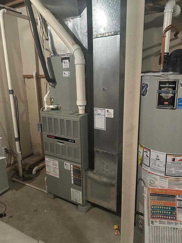 Completed comprehensive estimate for full HVAC system replacement including both furnace and air conditioning units. Assessed existing Trane furnace located in basement utility area along with current air conditioning system, documented equipment specifications, ductwork configuration, and installation requirements. Photographed existing equipment including furnace with PVC condensate drainage, metallic ductwork plenum, and associated mechanical components to provide accurate replacement pricing and system specifications for complete system changeout.