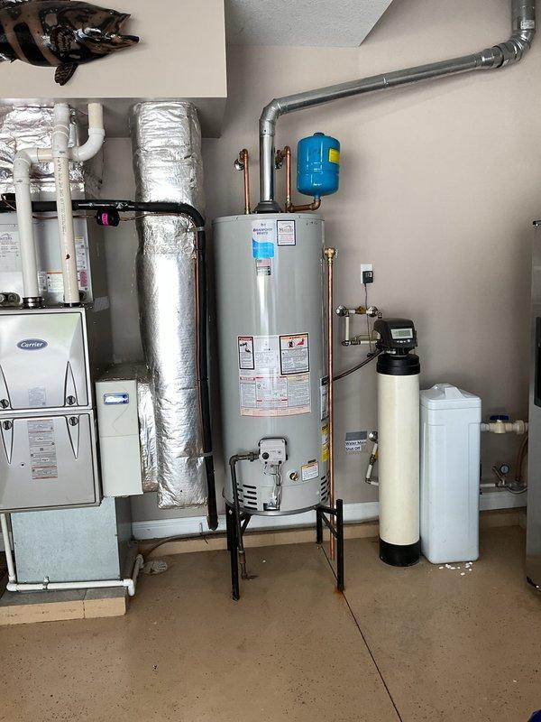 Installed a 50-gallon natural gas water heater in garage, mounting unit on an elevated stand as requested by property owner. Connected copper supply lines, installed blue expansion tank, and integrated gas control valve with temperature settings. Verified proper venting, tested pilot ignition system, and confirmed all connections were secure and operational per manufacturer specifications.