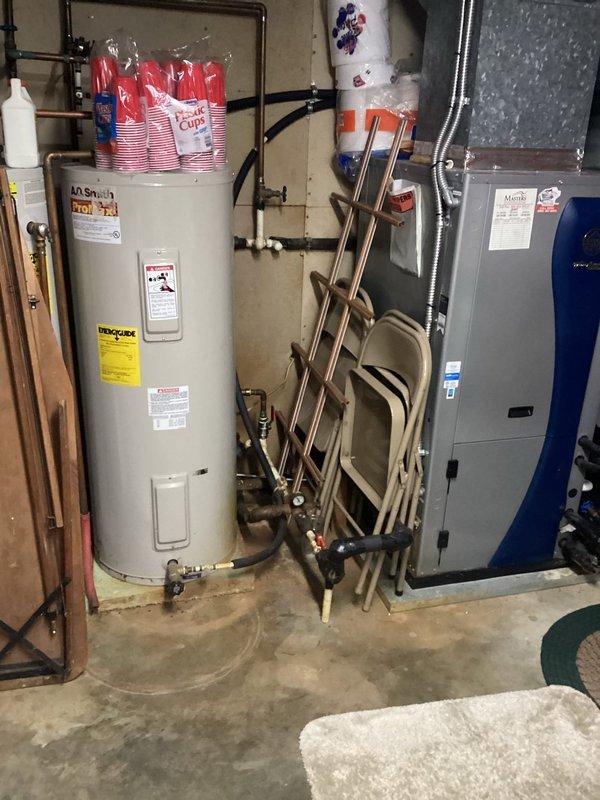 Responded to no cooling complaint on geothermal heat pump system. Upon arrival, performed diagnostic evaluation of the unit and associated components in basement mechanical room. Inspected geothermal system operation, verified electrical connections, examined refrigerant lines, and assessed loop pump functionality. Documented equipment conditions with photographs showing HVAC unit, water heater, plumbing connections, and mechanical room layout for service records.