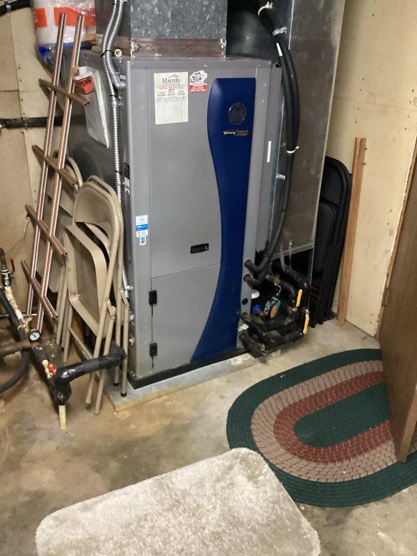 Responded to no cooling complaint on geothermal heat pump system. Upon arrival, performed diagnostic evaluation of the unit and associated components in basement mechanical room. Inspected geothermal system operation, verified electrical connections, examined refrigerant lines, and assessed loop pump functionality. Documented equipment conditions with photographs showing HVAC unit, water heater, plumbing connections, and mechanical room layout for service records.