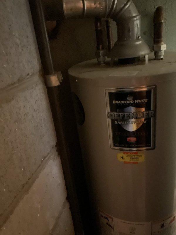 Provided estimate for replacement of existing 40-gallon gas-fired Bradford White Defender water heater located on main floor in confined space behind furnace. Evaluated tight working conditions, existing copper plumbing connections, galvanized metal venting system, and pressure relief valve configuration to determine scope of replacement work and access requirements.