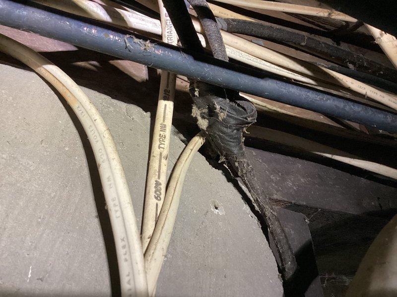 Completed preventive maintenance tune-up on air conditioning system in cooling mode. Inspected electrical panel, wiring connections, and associated components in utility area and attic space. Documented system conditions with photos showing electrical infrastructure and cable routing for maintenance records.