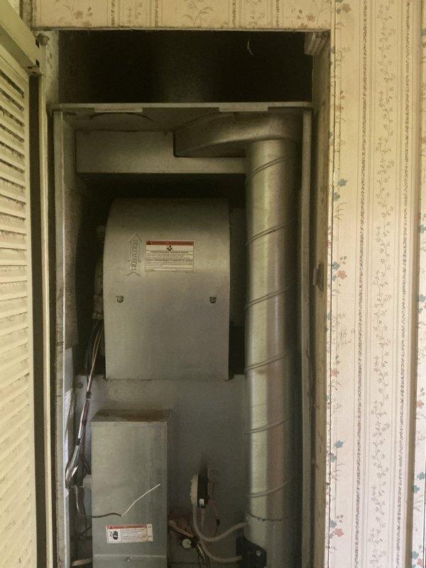 Completed on-site evaluation for central air conditioning system installation at residence currently relying on inadequate window units for cooling. Assessed existing furnace installation located in utility closet with vertical flue configuration. Documented current HVAC equipment, electrical service availability, and ductwork infrastructure to provide comprehensive replacement estimate for new central AC system. Provided multiple equipment options to address insufficient cooling capacity during high-temperature conditions.