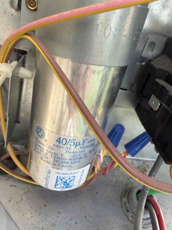 Completed routine cooling system maintenance inspection on residential HVAC unit. Inspected dual-run capacitor rated at 40/5µF 440VAC, verified proper electrical connections and wire terminations with secure wire nut connections. Examined compressor unit, confirmed all electrical wiring connections intact including proper routing of power and control wiring. All components operating within normal parameters with no issues identified during inspection.