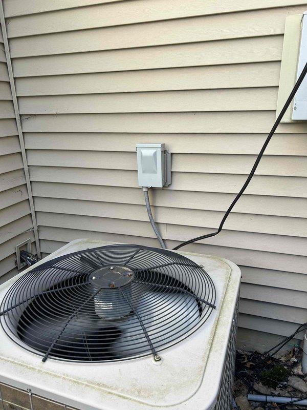 Performed comprehensive site evaluation for complete HVAC system replacement at residential property experiencing no cooling condition. Assessed existing outdoor condensing unit positioned on grade-level concrete pad against vinyl siding, noting weathered equipment with accumulated debris at base and standard electrical service connection via gray conduit and junction box. Evaluated indoor Bryant furnace system located in basement mechanical room with existing ductwork, PVC venting, and copper refrigerant lines. Documented current equipment specifications, electrical service requirements, and installation access points. Photographed existing equipment conditions and mechanical room layout to prepare detailed replacement estimate for new cooling and heating system installation.