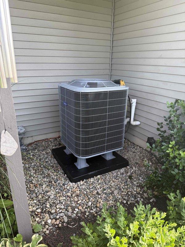 Successfully completed full HVAC system installation including a Carrier Comfort Series 27SCA530A003 single-stage heat pump outdoor unit, Carrier CVAVA3617XMA evaporator coil, and Honeywell ELITEPRO S1200 thermostat. Removed and recycled existing equipment from basement utility area, reconnected to existing line set after flushing and pressure testing to ensure proper refrigerant flow and system integrity. Installed new 2-inch PVC condenser pad with pea gravel base in exterior corner location, positioning unit on elevated rubber mounting pad with proper clearances for airflow and service access. Ran new low voltage wiring from indoor air handler to outdoor heat pump unit to accommodate heat pump operation and reversing valve control. Installed new electrical disconnect and whip at outdoor unit per code requirements. Reconnected existing supply and return ductwork to new evaporator coil, ensuring proper airflow and sealed connections. Performed system startup, verified proper refrigeran
