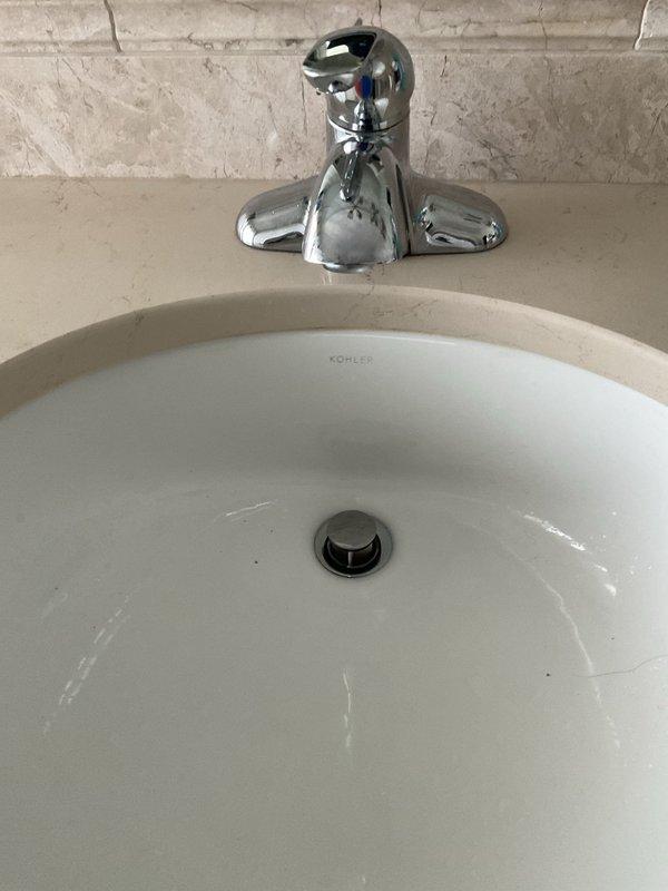Responded to service call for dripping faucets in bathroom and utility sink area. Disassembled bathroom faucet handles to access valve cartridge assemblies, which showed mineral deposits and wear causing the leak. Serviced the valve mechanisms and reassembled the chrome two-handle faucet on the Kohler undermount sink. Addressed dripping issues at multiple fixtures to restore proper operation and eliminate water waste.