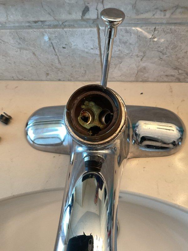 Responded to service call for dripping faucets in bathroom and utility sink area. Disassembled bathroom faucet handles to access valve cartridge assemblies, which showed mineral deposits and wear causing the leak. Serviced the valve mechanisms and reassembled the chrome two-handle faucet on the Kohler undermount sink. Addressed dripping issues at multiple fixtures to restore proper operation and eliminate water waste.