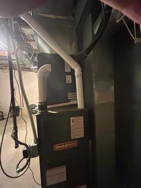 Conducted comprehensive HVAC system assessment for residential property following referral and previous service recommendation for unit replacement. Evaluated existing Goodman furnace installation in basement utility area, noting age and operational condition of current equipment. Assessed ductwork configuration including white insulated supply ducts and metallic flexible ducting connections. Examined electrical components and wiring associated with existing system. Inspected basement installation environment, documenting floor conditions, concrete surfaces, and utility pipe locations that may impact equipment placement. Reviewed both air conditioning and furnace replacement options to provide customer with complete system upgrade estimates. Photographed existing equipment installation, ductwork layout, and surrounding area conditions for replacement planning purposes. Provided detailed pricing options for air conditioning replacement as primary need, with additional furnace replacemen