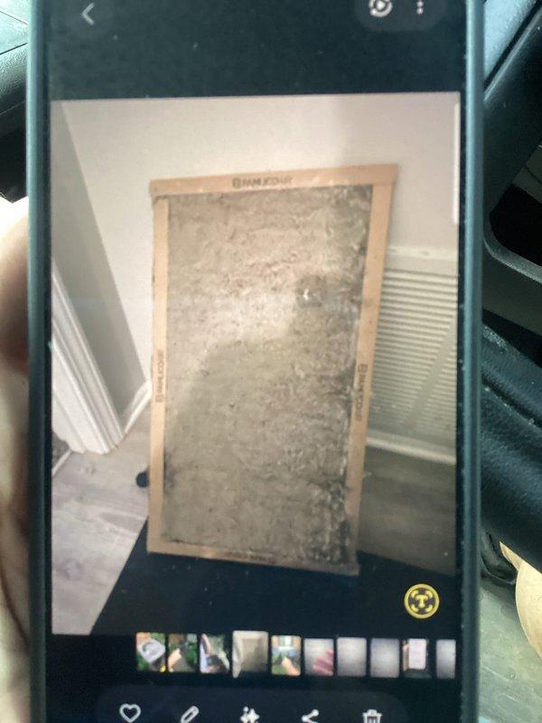 Responded to no cooling call on commercial R22 system over 10 years old. Found heavily clogged air filter restricting airflow to system. Documented existing outdoor condenser unit condition showing age-appropriate wear on beige unit with circular top grille positioned against brick exterior with surrounding vegetation. Replaced dirty filter to restore proper airflow and system operation.