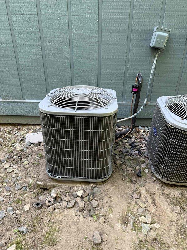 Completed full HVAC system installation including outdoor Carrier condensing unit and indoor air handler with evaporator coil. Installed condensing unit on prepared gravel pad with proper clearances, ran electrical whip to wall-mounted disconnect, and established refrigerant line connections. Mounted air handler vertically in side closet with PVC condensate drain lines and auxiliary drain pan assembly. Removed old equipment from site and delivered to maintenance office per work order specifications.