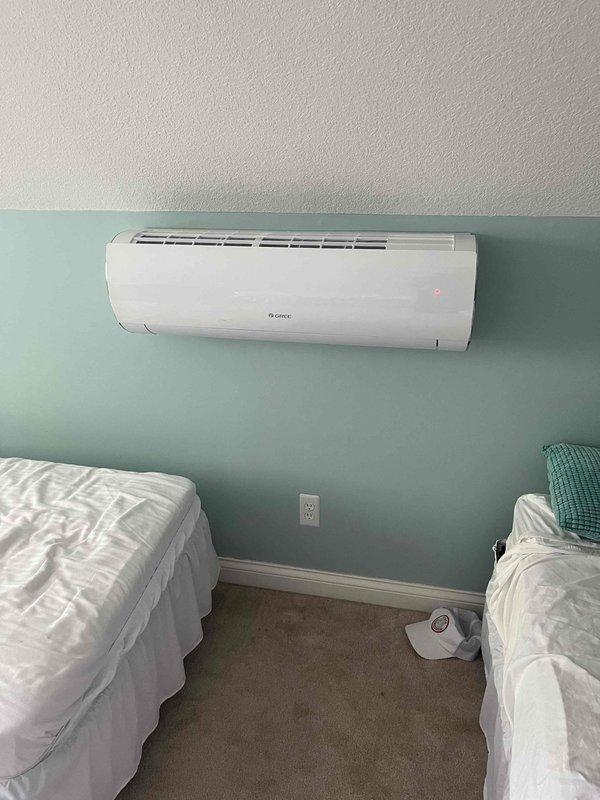 Responded to no cooling complaint on Gree ductless mini-split system serving upstairs south-facing bedroom. Upon inspection, found 10+ year old wall-mounted air handler and outdoor condenser unit with significant vegetation overgrowth restricting airflow to condenser. Unit displayed operational indicator lights but was not achieving adequate cooling capacity. Cleared hydrangea bushes and excess foliage from around condenser to restore proper airflow and ventilation clearances. Verified system operation and cooling performance after clearing obstruction. Addressed customer inquiry regarding why ductless units were installed in home with existing central air system; explained that mini-splits provide supplemental zone cooling for rooms with high heat gain or inadequate coverage from central system, particularly common for south-facing bedrooms with solar heat load.