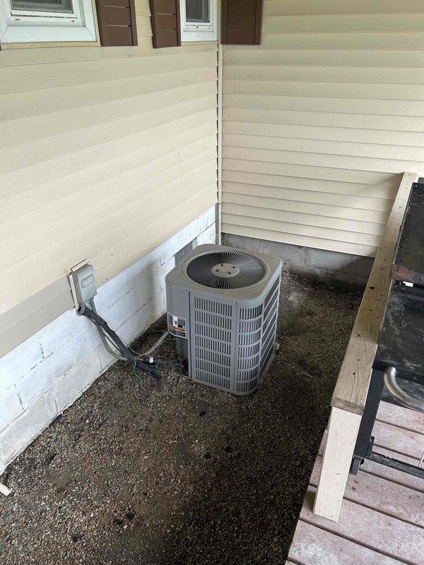 Responded to no-cooling complaint on all-electric residential property. Upon arrival, assessed existing cylindrical air conditioning condenser unit with gray metal exterior located on gravel pad adjacent to building foundation. Evaluated electrical disconnect, refrigerant line routing, and conduit connections. Inspected indoor mechanical space with louvered ventilation panels and noted environmental conditions within enclosed utility area. Presented heat pump replacement options to address failed cooling system, discussed financing alternatives, and provided comprehensive estimate for complete HVAC system replacement suitable for all-electric home configuration.