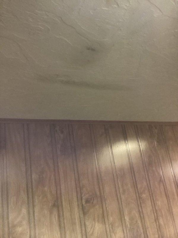 Responded to emergency water leak in basement originating from dishwasher supply line. Upon arrival, observed active water intrusion through ceiling light fixture and visible water staining along suspected water line path. Isolated leak source by shutting off dishwasher supply valve, which successfully stopped active water flow. Inspected utility connection area and documented water damage to ceiling materials and rust staining at pipe connections. Advised homeowner that ceiling access may be required for complete repair and assessment of supply line condition. Photographed affected areas including supply valve configuration and ceiling water damage for documentation purposes.