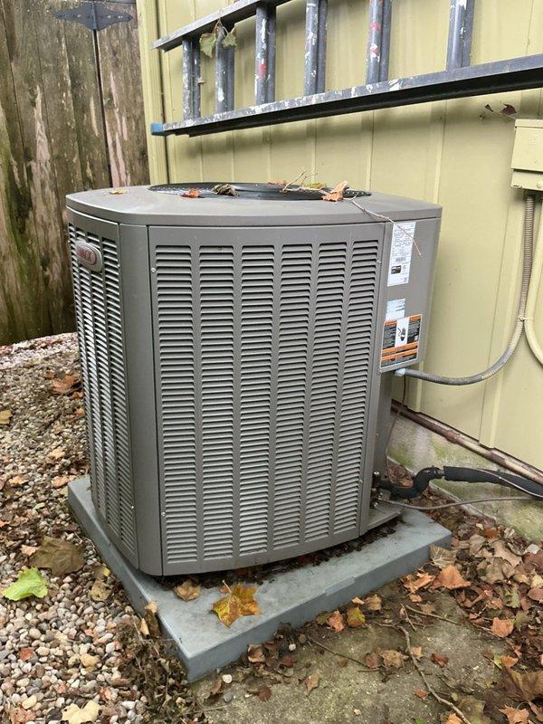 Conducted on-site evaluation of existing outdoor air conditioning condenser unit for replacement estimate. Inspected current unit positioned on concrete pad with river rock ground cover, noting accumulated seasonal debris and weathered copper refrigerant line connections to building exterior. Assessed unit specifications from manufacturer labels and documented existing installation configuration including electrical disconnect, line set routing along cream-colored vertical siding, and concrete pad condition. Measured clearance dimensions for replacement unit sizing requirements. Photographed current equipment setup and installation parameters to prepare comprehensive replacement quote for single AC unit as requested.