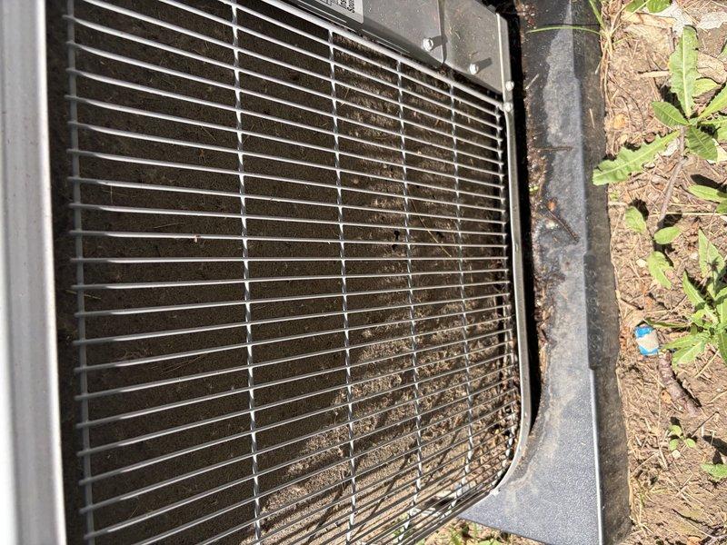 Responded to no cooling complaint on system installed less than one year ago. Upon arrival, inspected outdoor condensing unit and found excessive dirt and debris accumulation on condenser coil and grille assembly, restricting airflow. Cleaned condenser coil and surrounding components, removed obstructions from grille openings, and verified proper airflow restoration. System returned to normal cooling operation with adequate airflow through condenser unit.