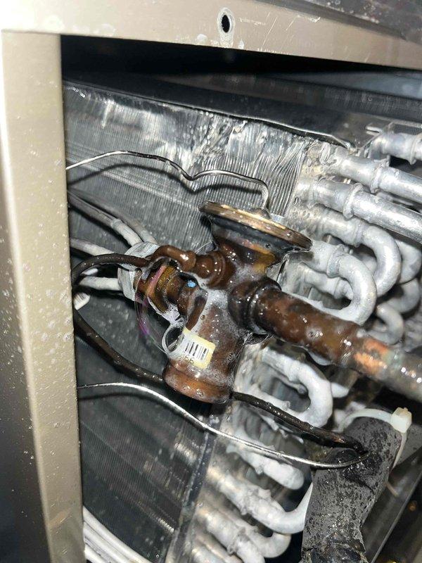 Responded to no cooling complaint on residential air conditioning unit. Upon inspection, found heavily corroded copper service valve and refrigerant fitting at evaporator coil with visible oxidation and green patina buildup. Evaporator coil showed signs of moisture accumulation and dirt buildup on aluminum fins. Documented equipment condition including model EMBD520 and compromised refrigerant connections that likely contributed to system's inability to produce cold air.